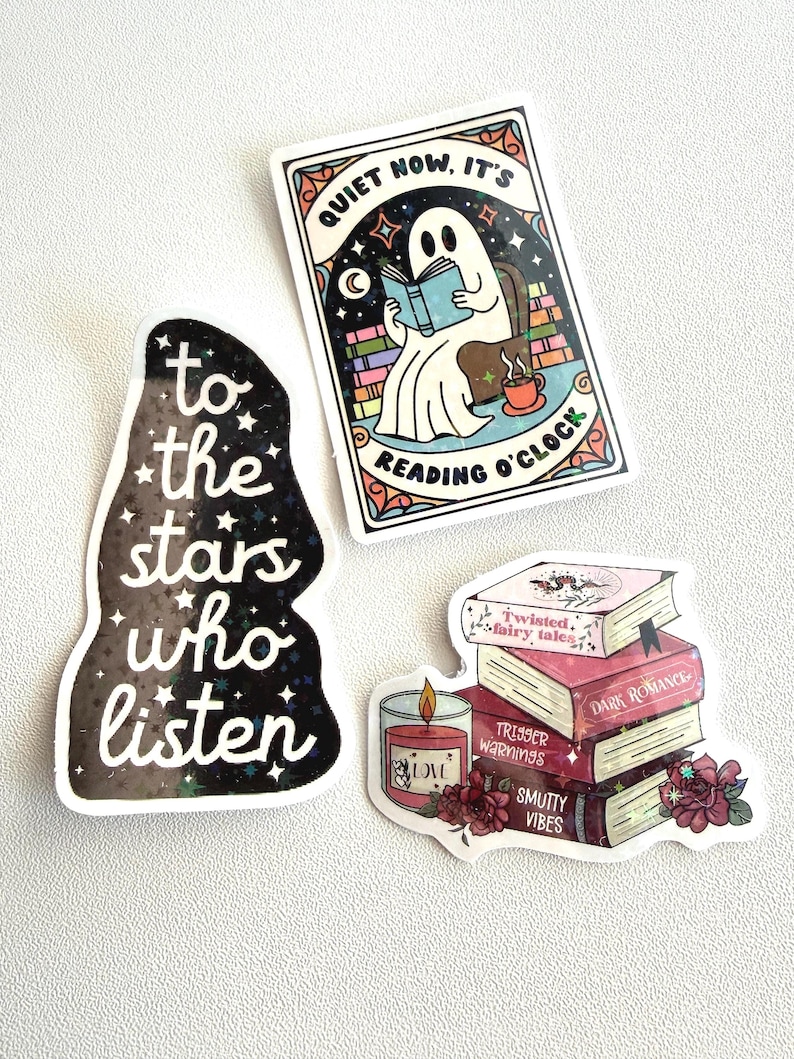 May include: Three stickers with a literary theme. One sticker features a ghost reading a book with the text "QUIET NOW, IT'S READING O'CLOCK". Another sticker says "to the stars who listen". The third sticker shows a stack of books and a candle.