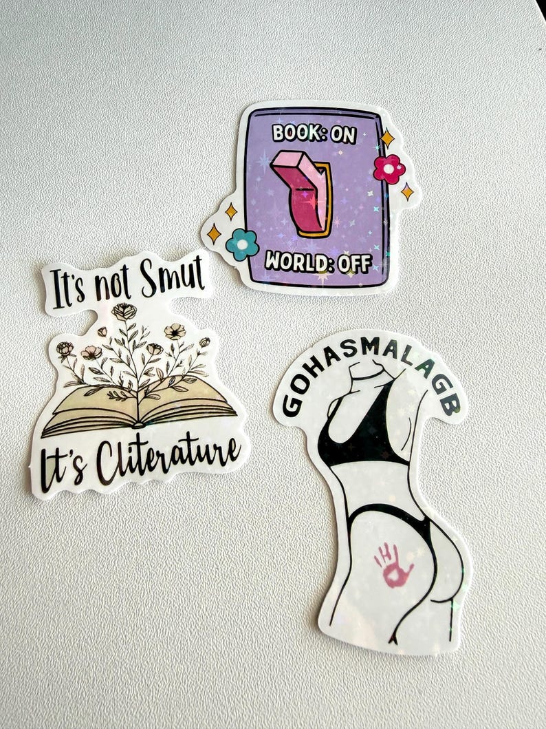 May include: A collection of four stickers with various designs. One sticker reads "It's not Smut". Another shows an open book with flowers and the text "It's Cliterature". A third sticker has a switch with the text "Book: On World: Off". The last sticker is a silhouette of a person in a bikini.
