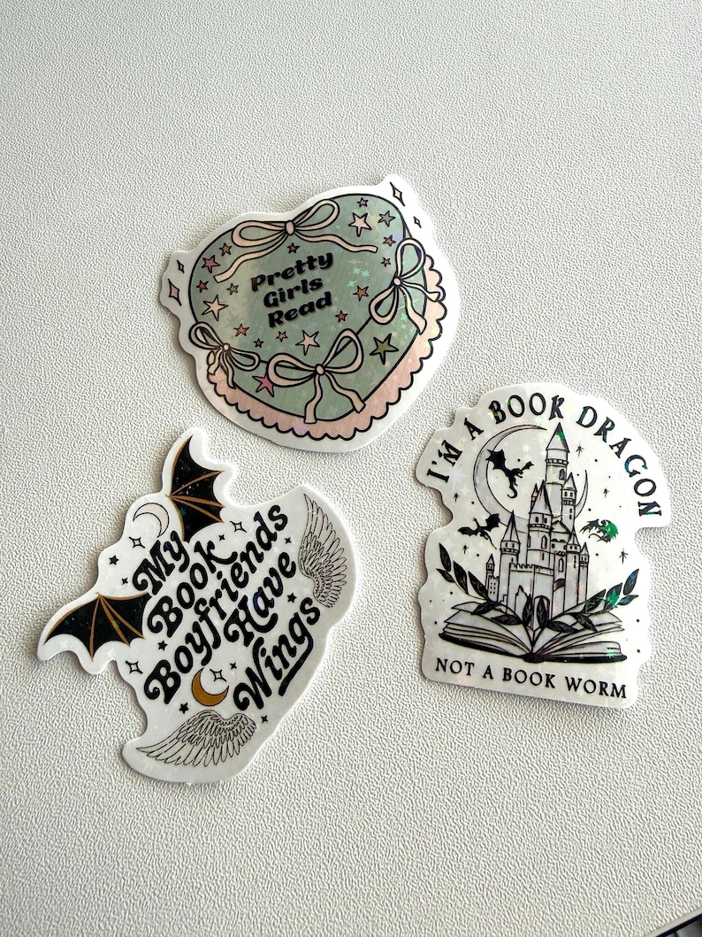 May include: Three stickers with book-themed designs. One is heart-shaped with the text "Pretty Girls Read". Another features a bat and the text "My Book Boyfriends Have Wings". The third shows a castle and the text "I'm a Book Dragon, Not a Book Worm".