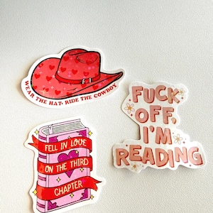 May include: A collection of stickers with a reading theme. One sticker features a red cowboy hat with heart accents and the text "WEAR THE HAT, RIDE THE COWBOY." Another shows a pink book with the text "FELL IN LOVE ON THE THIRD CHAPTER."