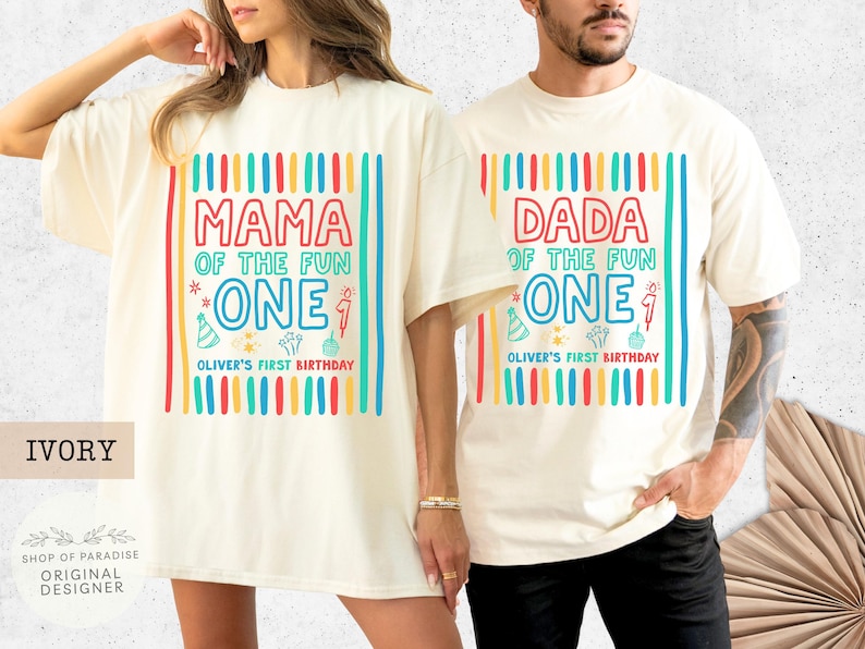 May include: Ivory-colored t-shirts with colorful text and graphics. One shirt reads "MAMA OF THE FUN ONE" and the other reads "DADA OF THE FUN ONE." Both shirts include "OLIVER'S FIRST BIRTHDAY" text and birthday-themed graphics.