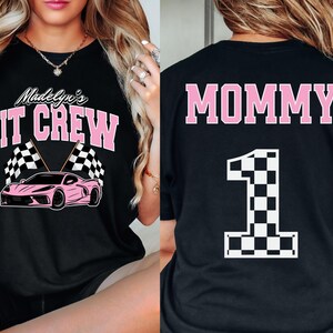May include: Black t-shirt with pink text that says "Madelyn's Pit Crew" and a pink race car with checkered flags. The back of the shirt has pink text that says "Mommy" and a large checkered number "1".