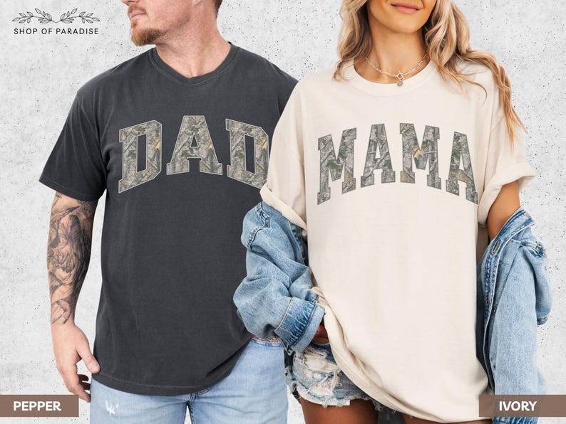 Puede incluir: Dos camisetas de manga corta, una color pimienta y otra color marfil. La palabra "DAD" est&aacute; impresa en la camiseta color pimienta, y la palabra "MAMA" est&aacute; impresa en la camiseta color marfil. Ambas palabras tienen un patr&oacute;n de camuflaje.
