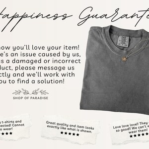 May include: A gray t-shirt with a small tag and a delicate necklace with a pendant. The image includes text that reads "Happiness Guarantee" and customer reviews. The shop name "SHOP OF PARADISE" is also visible.