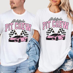 May include: Two white t-shirts with pink text that reads "Madelyn's Pit Crew" and a pink race car with checkered flags.