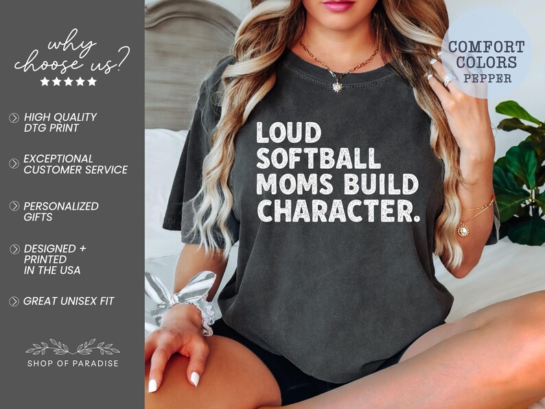 May include: Dark gray t-shirt with the text "LOUD SOFTBALL MOMS BUILD CHARACTER" in white. The shirt also features the text "COMFORT COLORS PEPPER". The shirt is part of the Shop of Paradise collection.