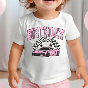 May include: A white t-shirt with a pink race car graphic and the text "Birthday Girl" in pink letters.