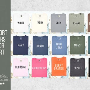 Puede incluir: Una carta de colores que muestra camisetas Comfort Colors en varios tonos. Las camisetas est&aacute;n dispuestas en filas y columnas, mostrando colores como blanco, marfil, gris, caqui, marino, denim, azul vaquero, musgo y negro. El texto "Comfort Colors Color Chart" es visible.