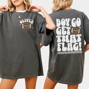May include: Two gray t-shirts with a football graphic. The front shirt says "Oliver" and the back shirt says "Boy go get that flag!"