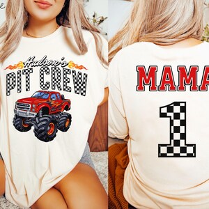 Pu&ograve; includere: Due magliette bianche a tema corse. Una maglietta presenta un monster truck rosso con il testo "Hudson's Pit Crew". L'altra maglietta ha il testo "MAMA" e una bandiera a scacchi numero uno.