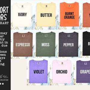 K&ouml;nnte beinhalten: Eine Comfort Colors Farbkarte mit elf T-Shirts in verschiedenen Farbt&ouml;nen: Elfenbein, Butter, gebranntes Orange, Yam, Espresso, Moos, Pfeffer, Schwarz, Violett, Orchidee und Traube. Jedes T-Shirt ist mit dem entsprechenden Farbnamen in Schwarz beschriftet.
