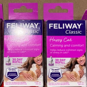 Puede incluir: Cuatro cajas rectangulares idénticas de recambios Feliway Classic Happy Cat para difusor, que ofrecen calma y confort durante 30 días. Cada caja morada y blanca muestra texto, un vial de difusor y una persona sosteniendo un gato.