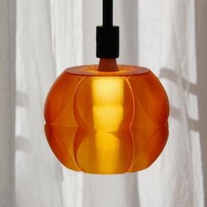 Könnte beinhalten: Orangefarbene Pendelleuchte mit kugelförmigem, blütenblattförmigem Schirm. Sie hängt an einer schwarzen Stange und strahlt warmes Licht aus. Die Leuchte ist ein modernes Design, geeignet für die Inneneinrichtung.