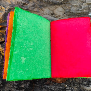 May include: A handmade journal with a green cover and a red cover. The journal is made of recycled paper and has a leather strap.