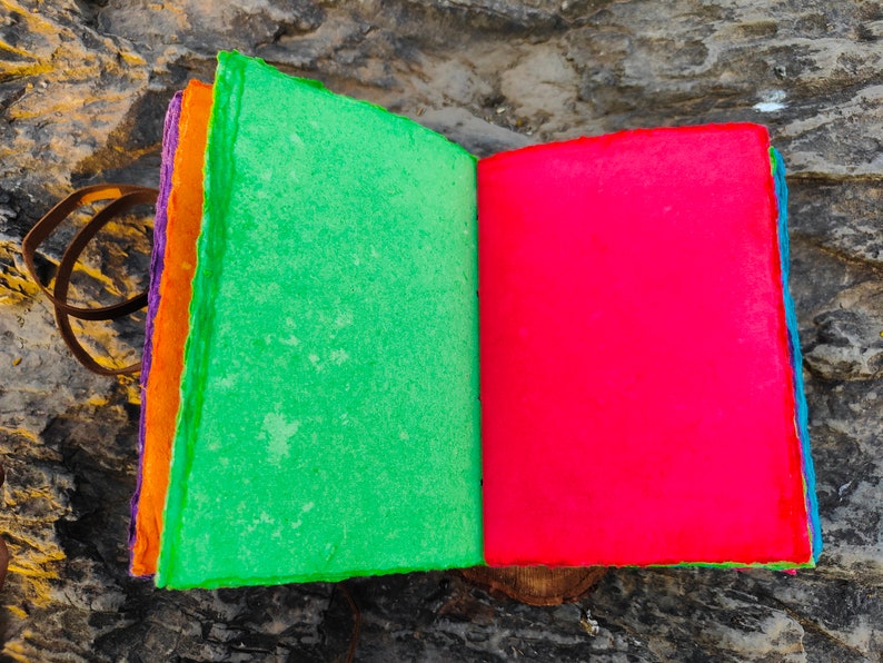 May include: A handmade journal with a green cover and a red cover. The journal is made of recycled paper and has a leather strap.