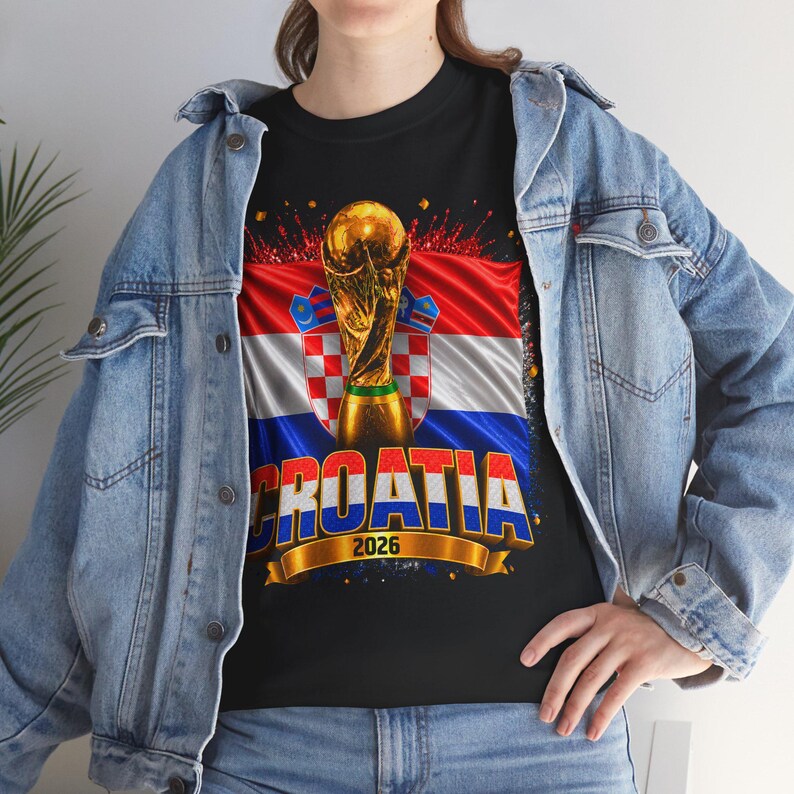 Black t-shirt worn by a male model featuring a Croatia football-themed design with the FIFA World Cup trophy, Croatian flag, and bold “CROATIA 2026” text on the front.