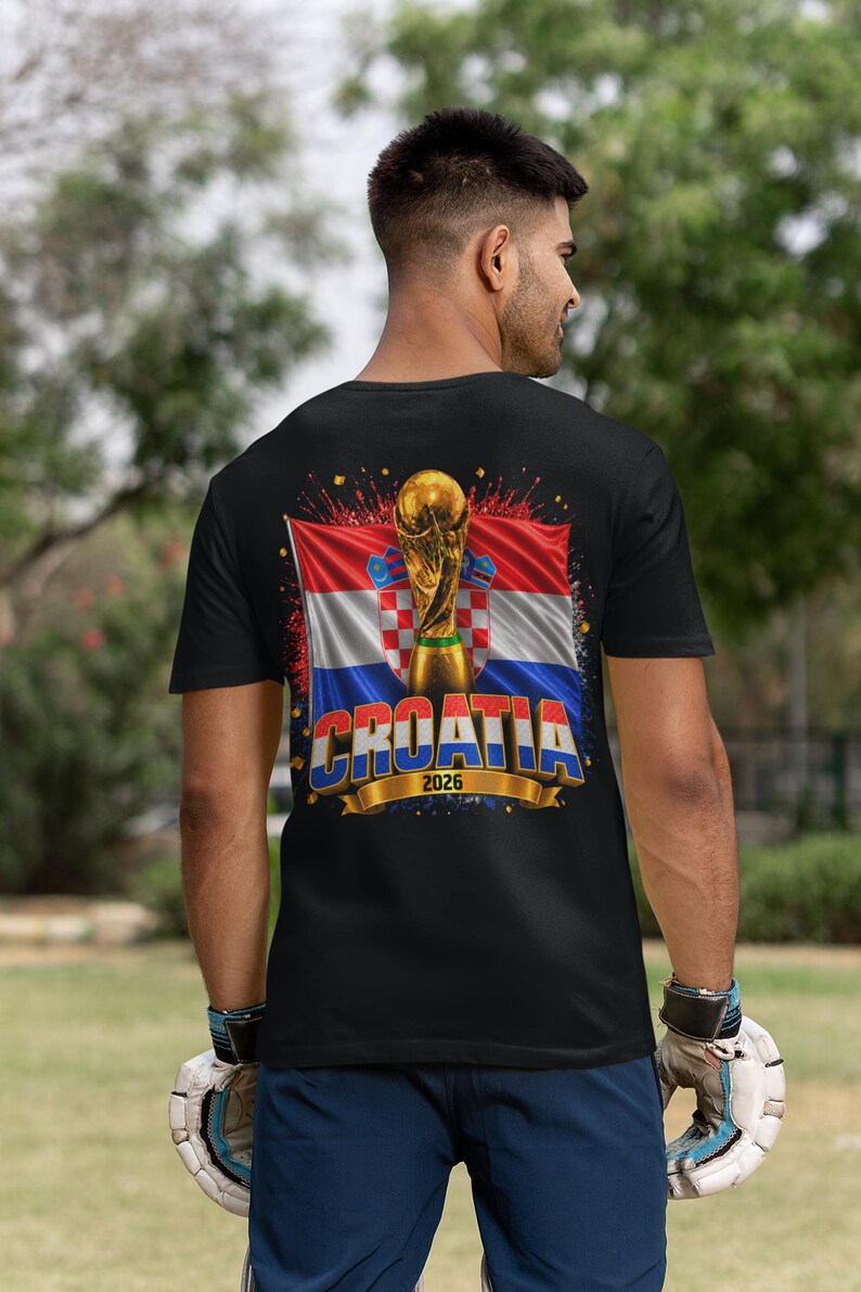 Black t-shirt worn by a male model featuring a Croatia football-themed design with the FIFA World Cup trophy, Croatian flag, and bold “CROATIA 2026” text on the front.