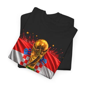 Black t-shirt worn by a male model featuring a Croatia football-themed design with the FIFA World Cup trophy, Croatian flag, and bold “CROATIA 2026” text on the front.