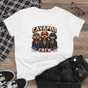 Puede incluir: Camiseta blanca con un gráfico de tres perros Cavalier King Charles Spaniel con chaquetas de cuero y bandanas. El texto "Cavapoo Crew" está impreso debajo de los perros.