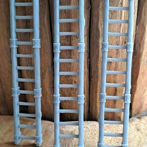 May include: Three gray wooden ladders with metal accents. The ladders are made of wood and have a rustic look.