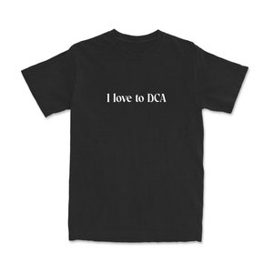 Puede incluir: Camiseta negra con texto blanco que dice "Me encanta DCA".