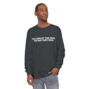 May include: A dark gray long-sleeve shirt with the text "You come at the king, you best not miss" printed in white on the front.