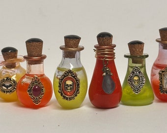 May include: Seven small glass bottles with cork stoppers and various colored liquids. Each bottle has a decorative metal charm with a Halloween theme, including a skull, a bat, a spider, and a gemstone.