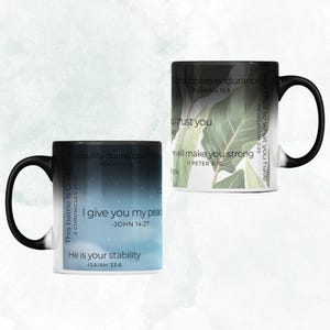 May include: Two black and white color-changing mugs with inspirational quotes and bible verses. The mug on the left has a blue and white sky background with the text "This battle is God's - 2 Chronicles 20:15", "Tranquility during calamity - Psalm 114:12", "I give you my peace - John 14:27", and "He is your stability - Isaiah 33:6". The mug on the right has a green and white leafy background with the text "God supplies endurance - Romans 15:5", "Hold fast to what you have - Revelation 2:25", "I trust you", and "He will make you strong - 1 Peter 5:10".