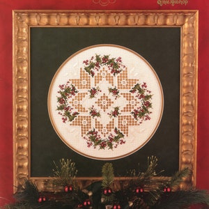 Pode incluir: Um design de ponto cruz emoldurado com um padrão de estrela de Natal. O design é em forma de estrela com uma grinalda de azevinho e bagas. A moldura é dourada, contra um fundo verde escuro, com uma borda vermelha. O texto "CROSS 'N PATCH" e "Christmas Star" é visível.