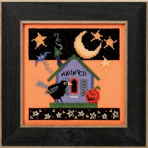 May include: A cross-stitch pattern featuring a purple haunted house with a black crow perched on the roof. The house has a sign that reads "Haunted". The background is a dark orange with a crescent moon and stars.