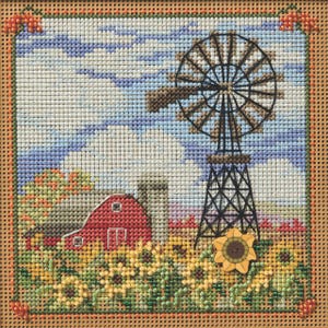 May include: A cross-stitch embroidery of a red barn with a silo, a windmill, and a field of sunflowers. The sky is blue with white clouds.