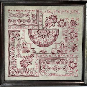 Puede incluir: Una pieza de bordado enmarcada con fondo blanco y un diseño floral rojo. El diseño está compuesto por varios motivos florales, incluyendo flores, hojas y tallos. El bordado está enmarcado en un marco de madera oscura.