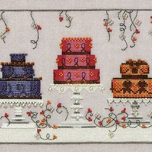 May include: Three decorated cakes on white cake stands with white frosting and colorful decorations. The cakes are on a white surface with black vines and red berries.