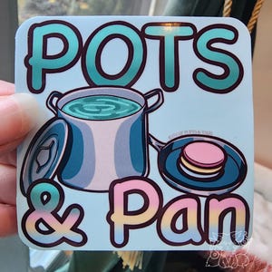 May include: A blue and white sticker with the text "POTS & Pan" in a rainbow gradient. The sticker features a cartoon illustration of a pot with a lid and a pan with a stack of pink and white macarons.