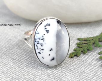 May include: A silver ring featuring a white and black dendritic agate oval stone. The ring is set in a silver band.