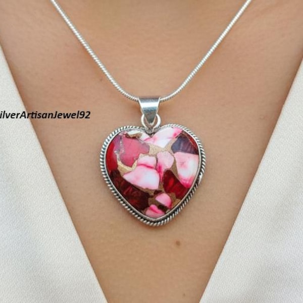 May include: A heart-shaped pendant featuring a mosaic of red and white stone fragments set in a silver frame, suspended from a thin silver chain. The text SilverArtisanJewel92 is visible on the left side of the pendant against a white fabric.