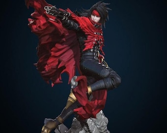 Op de afbeelding: Gedetailleerd beeldje van een personage in een dynamische pose, met een rode cape en zwarte outfit. Het beeldje houdt een pistool vast en staat op een rotsachtige basis. Het personage heeft zwart haar en een rode hoofdband. Het ontwerp is zeer gedetailleerd.