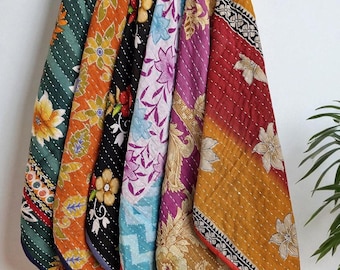 May include: A collection of seven colorful, patterned fabric items hanging on a wooden rack. Each item features a unique floral design in shades of green, orange, black, blue, purple, and red. The fabrics are stitched with white thread, creating a quilted effect.