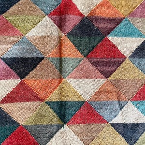 May include: A colorful rug with a geometric pattern of triangles in shades of red, orange, yellow, green, blue, purple, and brown.