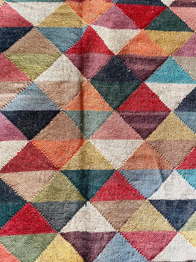 May include: A colorful rug with a geometric pattern of triangles in shades of red, orange, yellow, green, blue, purple, and brown.
