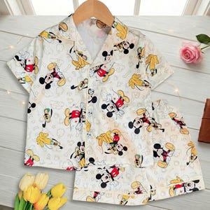 May include: A white ceramic mug with a black handle and the text "But First, Coffee" in a bold, black font. The mug is set against a neutral background, highlighting its simple design.