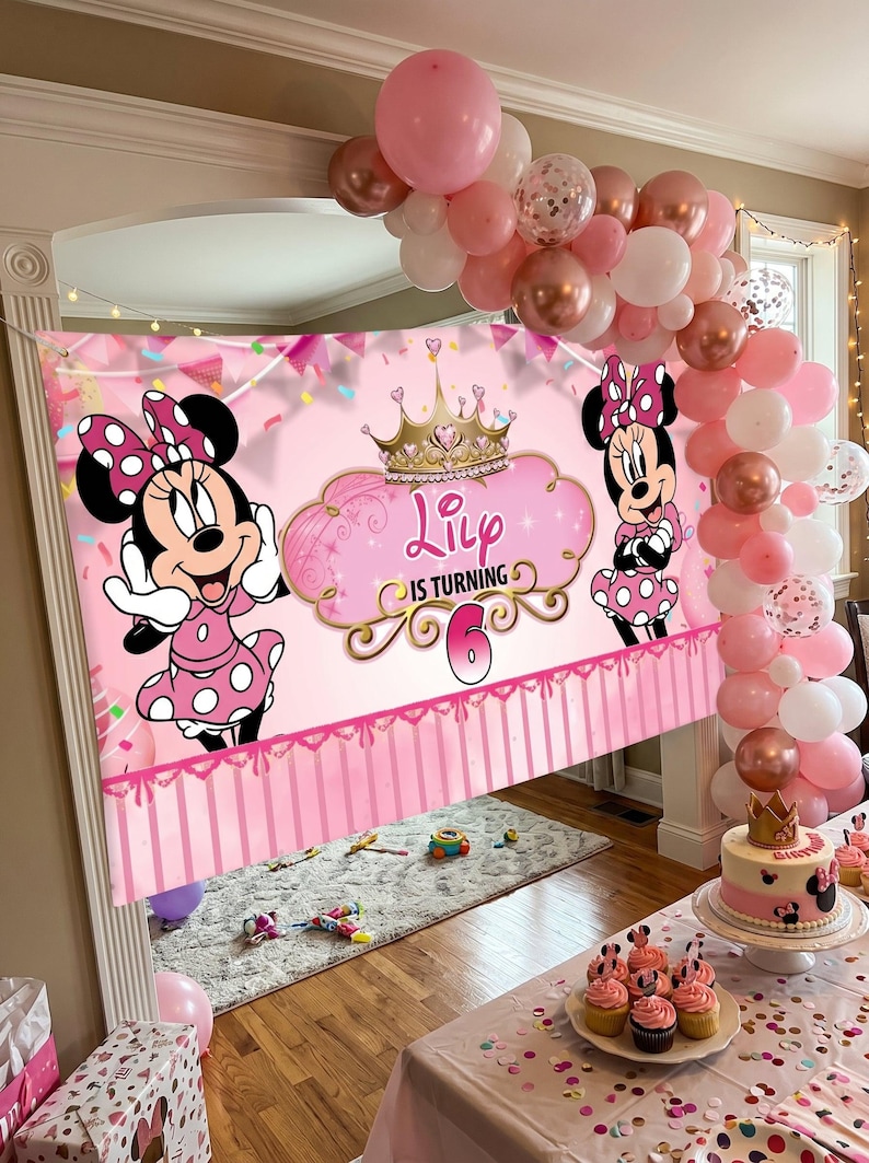 May include: A pink Minnie Mouse-themed birthday party scene. A banner with Minnie Mouse graphics and the text "Lily is turning 6" is displayed. Balloons in pink, white, and rose gold decorate the area, along with a cake and cupcakes.