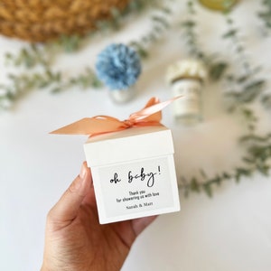 There are colorful artificial flowers on the glass candle made with soy wax. There is a customizable label on the cup.