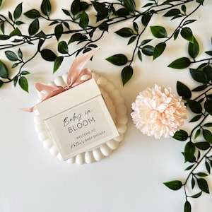 There are colorful artificial flowers on the glass candle made with soy wax. There is a customizable label on the cup.