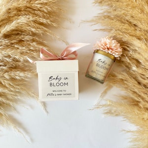 There are colorful artificial flowers on the glass candle made with soy wax. There is a customizable label on the cup.
