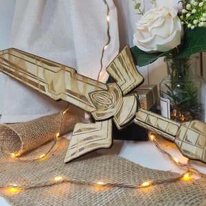 Op de afbeelding: Een houten zwaard met ingewikkelde details, dat lijkt op een videogamewapen. Het zwaard ligt op een jute oppervlak met lichtslingers.
