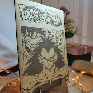May include: A wooden plaque with a laser-engraved image of three characters from the Dragon Ball anime series. The characters are Vegeta, Goku, and Piccolo. The plaque has the text "Dragon Ball" at the top.