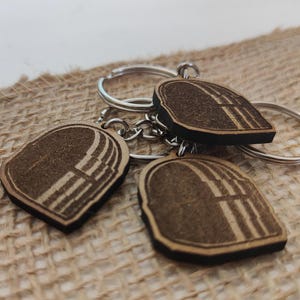 Puede incluir: Tres llaveros de madera con un diseño geométrico. Cada llavero está unido a un anillo de llave plateado.