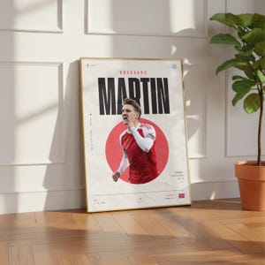 May include: A vertical poster featuring a photograph of Martin Odegaard in a red and white soccer jersey, centered within a red circle. The name MARTIN is printed in large black letters above the image, with additional text and the Norwegian flag.