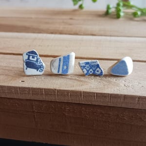 Könnte beinhalten: Vier kleine Keramikstücke mit blauen und weißen Mustern. Die Stücke sind in einer Reihe auf einer Holzoberfläche angeordnet.